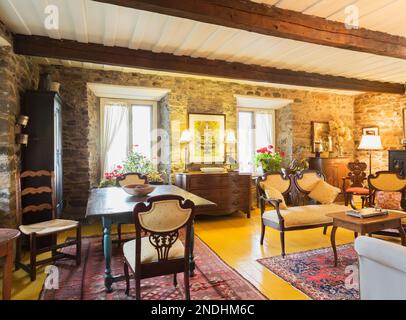 Tavolo da pranzo antico, amorino e poltrona in fleur-de-lys degli anni '1900 e tavolino da caffè in legno nel soggiorno all'interno della vecchia casa del 1650 ristrutturata. Foto Stock