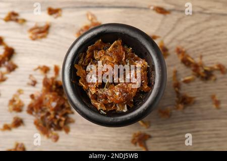 Ciotola di argilla di narghilè con tabacco aromatico su tavolo di legno, vista dall'alto Foto Stock