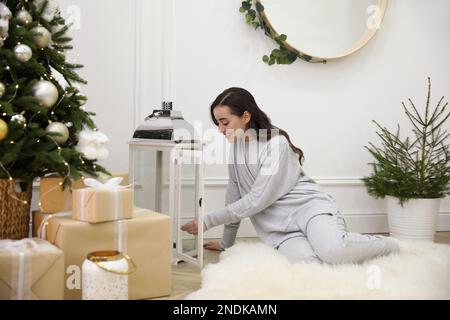 Donna che illumina le candele sul pavimento a casa Foto Stock