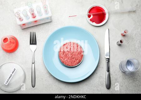 Carne coltivata servita su un tavolo da laboratorio grigio chiaro, piatto Foto Stock