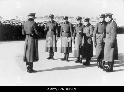 Membri dell'unità di guardia del campo Totenkopf nel campo di concentramento di Sachsenhausen. I prigionieri possono essere visti allineati sullo sfondo. L'unità di guardia Totenkopf era un'unità separata all'interno delle SS ed era responsabile della gestione dei campi di concentramento e di sterminio. Si distinguono per l'emblema della testa della morte sul loro bavero. La divisione SS Panzer del 3rd portava il nome di Totenkopf, ma era un'unità combattente non coinvolta nell'amministrazione dei campi. Con Bundesarchiv, Bild 183-78612-0010 / CC-BY-SA 3,0, CC BY-SA 3,0 de, https://commons.wikimedia.org/w/index.php?curid=5431255 Foto Stock