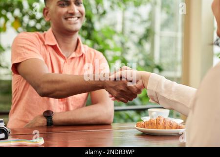 Giovane uomo positivo che scuote la mano del collega prima dell'incontro Foto Stock