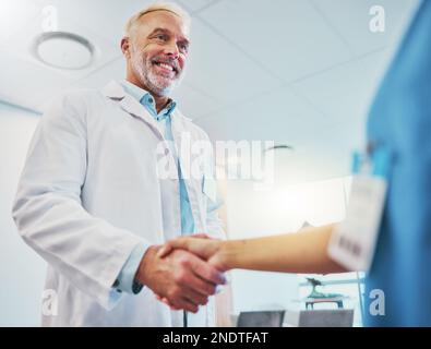 Assistenza sanitaria, stretta di mano e medico in collaborazione con un infermiere per una consultazione in ospedale. Felice, sorridere e assistente medico senior che scuote le mani Foto Stock