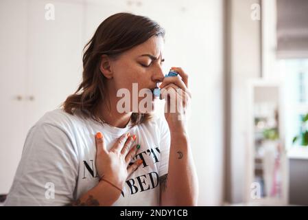 Non posso respirare. una bella giovane donna che usa il suo inalatore per asma. Foto Stock