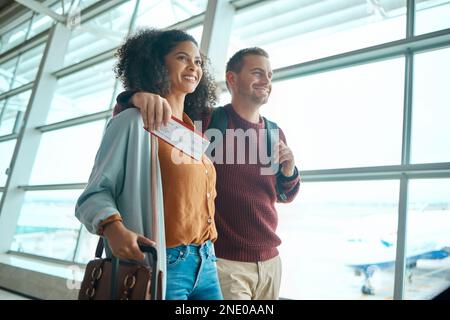 Viaggi, aeroporto e coppia felice con biglietto o carta d'imbarco per voli internazionali per destinazioni di vacanza insieme. Sorridi, donna e uomo con Foto Stock