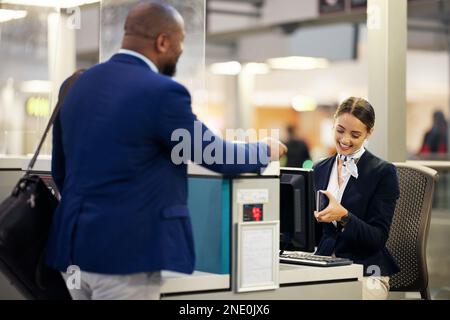 Uomo d'affari, assistente aeroportuale e passeggero che controlla i documenti del passaporto per il check-in allo sportello del terminal. Viaggiatore nero maschio e agente di servizio in Foto Stock