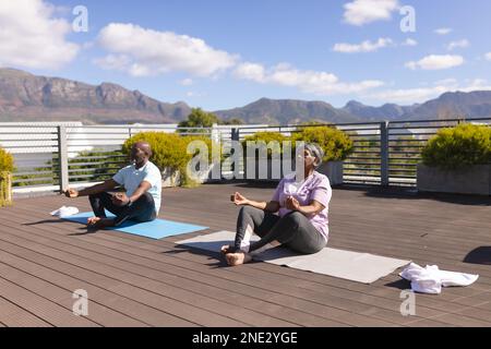 Coppia afroamericana senior che pratica yoga e meditare insieme sulla terrazza a casa. stile di vita e concetto di vita senior in pensione Foto Stock