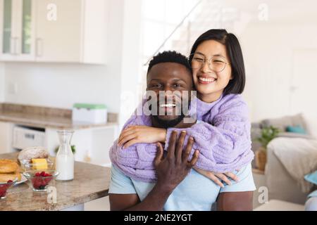 Ritratto di felice coppia varia abbracciando in cucina. Trascorrere il tempo di qualità a casa, la vita domestica e il concetto di stile di vita. Foto Stock