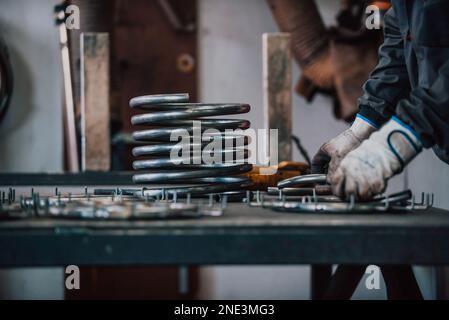 Primo piano di un uomo in guanti lucidando materiali di ferro in un settore Foto Stock