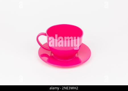una tazza di plastica rosa con piattino su fondo bianco Foto Stock