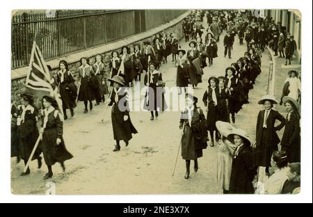 Le truppe patriottiche originali delle guide delle ragazze e degli scout del ragazzo che sfilano attraverso una città, marciando con una bandiera del Jack dell'Unione, rally pubblico di scouting, alcuni degli onlookers stanno portando un nastro del lapel, circa 1912, Regno Unito Foto Stock