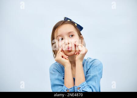 Sorridente bambina fare trend mini segno di cuore con le dita in abito denim casual isolato su sfondo bianco, studio, fa l'icona dell'amore, gesto con Foto Stock