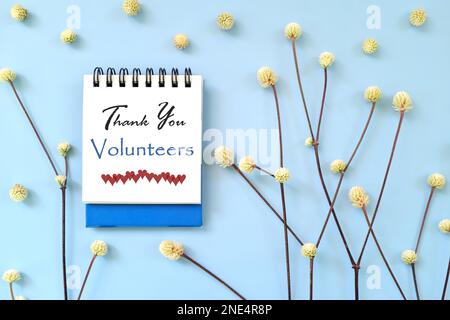 Grazie Volontarii messaggio su carta blu blocco note con design minimalista naturale. Foto Stock