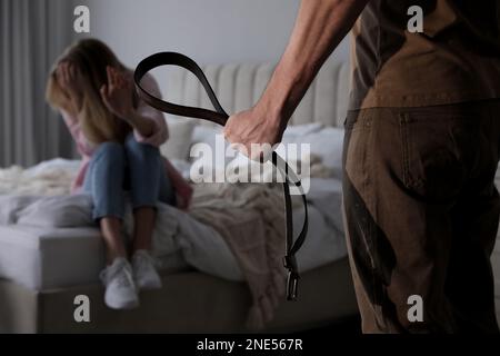 Uomo che minaccia la donna con la cintura interna, primo piano. Violenza domestica Foto Stock