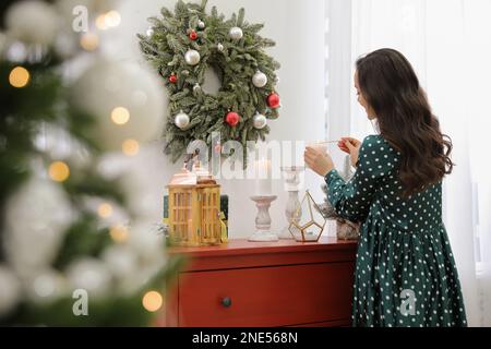 Donna che illumina le candele a casa. Natale Foto Stock