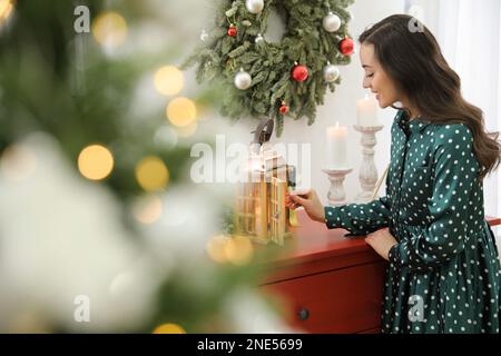 Donna che illumina le candele a casa. Natale Foto Stock