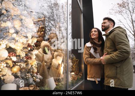 Bella coppia vicino a un negozio decorato per Natale all'aperto Foto Stock