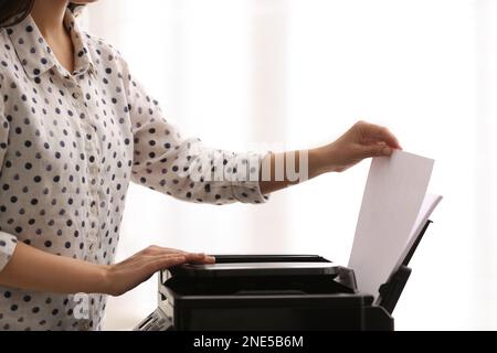 Dipendente che utilizza una stampante moderna in ufficio, in primo piano Foto Stock