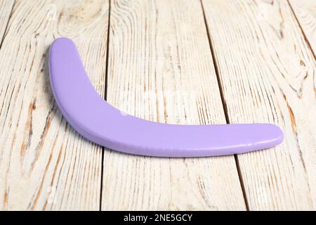 Boomerang viola su sfondo di legno bianco. Attività all'aperto Foto Stock