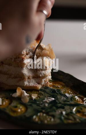 Processo di mangiare cremoso torta di mandorle in cucina Foto Stock