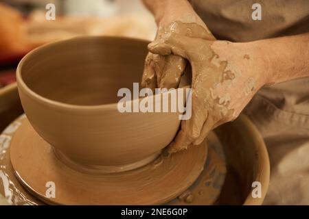 Ceramista fare una ciotola con le mani su una ruota in uno studio Foto Stock