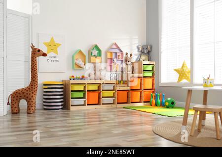 Elegante interno della sala giochi con scaffalatura e diversi giocattoli morbidi Foto Stock