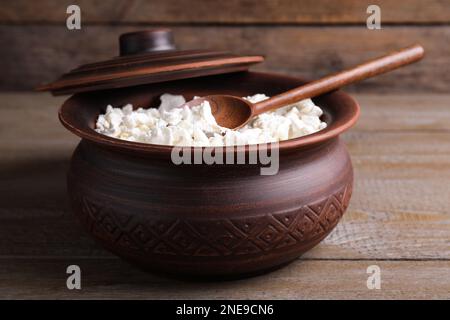 Pentola di argilla con formaggio di ricotta e cucchiaio su tavolo di legno grigio Foto Stock