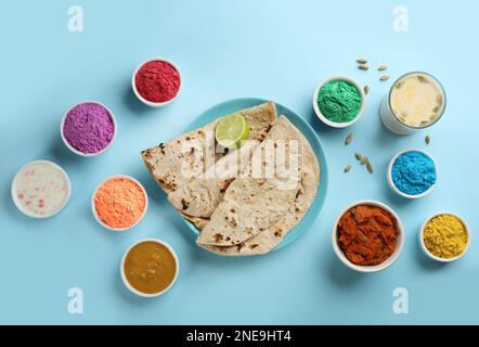 Cibo tradizionale indiano e coloranti in polvere colore su sfondo turchese, piatto. Festa di Holi Foto Stock