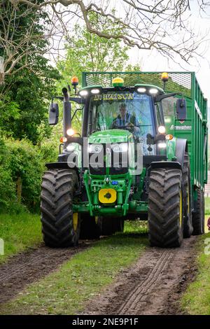 Il trattore John Deere conduce un rimorchio pieno di erba appena raccolta al morsetto per insilato in un'azienda lattiero-casearia di Dumfries, Scozia, Regno Unito. Foto Stock