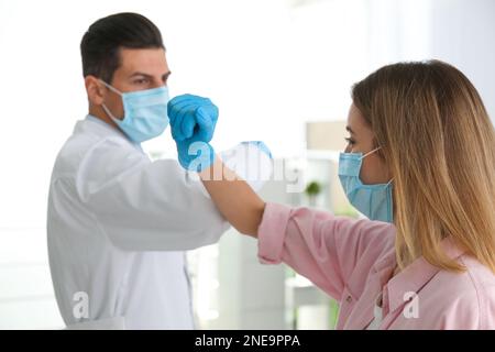 Il medico e il paziente fanno un urto del gomito invece di una stretta di mano in clinica. Nuovo saluto durante la pandemia COVID-19 Foto Stock