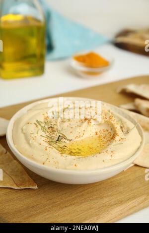 Delizioso hummus servito con patatine pita su asse di legno Foto Stock