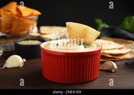 Delizioso hummus con patatine pita su tavolo di legno, primo piano Foto Stock