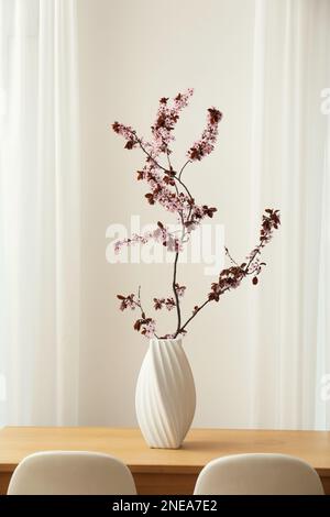 Albero in fiore ramoscello in vaso su tavolo di legno al coperto Foto Stock