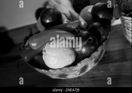 Ciotola di frutta contenente finocchio , prugne , peperoncini rossi e limoni in monocromia Foto Stock
