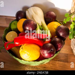 Ciotola di frutta contenente finocchio , prugne , peperoncini rossi e limoni Foto Stock
