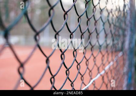 Primo piano su una recinzione a catena con un campo da tennis sullo sfondo. L'immagine orizzontale si trova nella foresta. Foto Stock