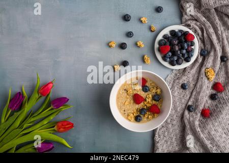 Concetto di colazione sana con fiocchi di avena e frutti di bosco freschi su sfondo rustico. Cibo fatto di granola, muesli. fragole, mirtilli Foto Stock