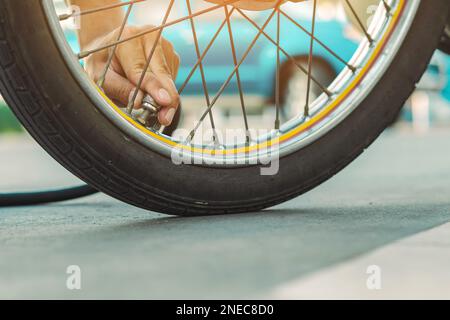Mani di un uomo controllare la pressione del generatore di gas e gonfiare uno pneumatico su una motocicletta con un compressore pneumatico. Man controllo della pressione dell'aria e riempimento della pressione dei pneumatici Foto Stock