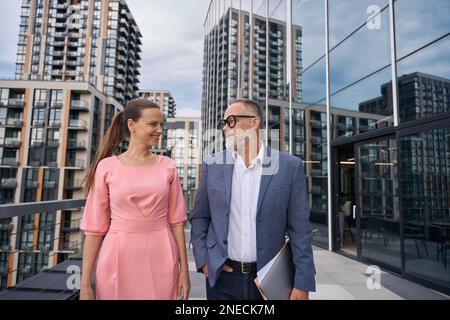 Uomo e donna di mezza età in abito elegante passeggiata lungo la terrazza Foto Stock