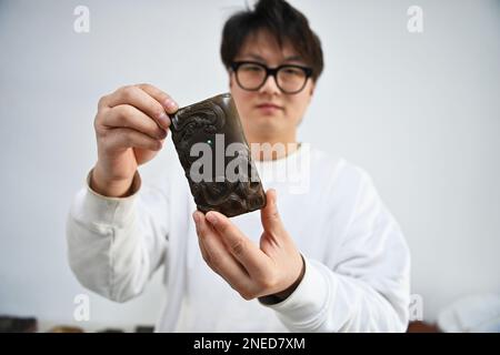 (230216) -- YUNCHENG, 16 febbraio 2023 (Xinhua) -- Lin Xiaolin espone una inkstone di Chengni progettata da lui in uno studio nella contea di Xinjiang di Yuncheng, provincia di Shanxi della Cina settentrionale, 15 febbraio 2023. Chengni inkstone, uno dei "quattro famosi inkstone" in Cina, è noto per la sua consistenza fine che può ridurre il danno fatto al pennello. A causa di varie ragioni, il tempo-onorato mestiere di fabbricazione di Chengni inkstone era stato perso una volta ed è stato portato più successivamente indietro da Lin Yongmao e da suo figlio Lin Tao nella contea di Xinjiang. Ci vogliono più di un anno e più di 10 passi per fare un Inkstone Chengni. Nel 2008, il mestiere Foto Stock