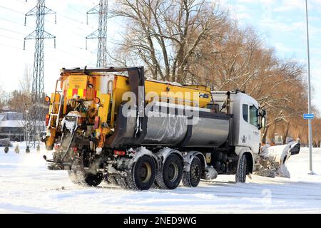 Scania Truck equipaggiato con spazzaneve e spargitore di sale stradale in movimento dopo la nevicata invernale nel sud della Finlandia. Salo, Finlandia. Febbraio 11, 2023. Foto Stock