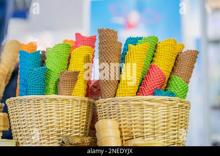 Coni di gelato vuoti in colori assortiti per diversi gusti di primo piano di gelato. Scena reale nella gelateria Foto Stock