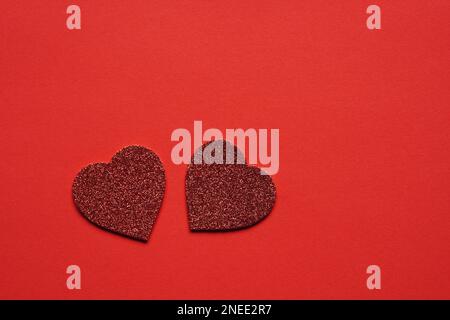 Due a forma di cuore cuori glitter su sfondo rosso con spazio copia - il giorno di San Valentino il matrimonio o un anniversario concetto Foto Stock