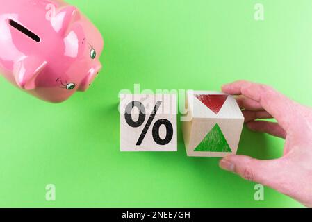 cambiamenti nel concetto finanziario dei tassi di interesse, vista dall'alto del segno di percentuale e simbolo della freccia sui cubi di legno oltre a piggy bank Foto Stock