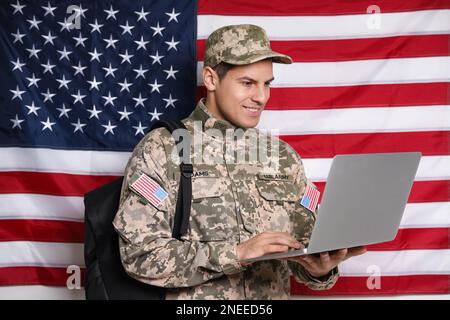 Cadet con zaino e laptop contro la bandiera americana. Educazione militare Foto Stock