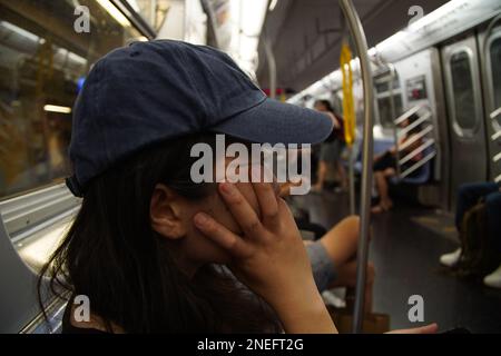 Una donna si sposta da sola sulla metropolitana di New York. Foto Stock