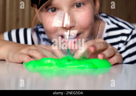 Giocare con slime testurizzato con bolle, stretching la sostanza gooey. Femmina teen mano che tiene blu brillante slime, schiacciandolo. Adorable Girl str Foto Stock