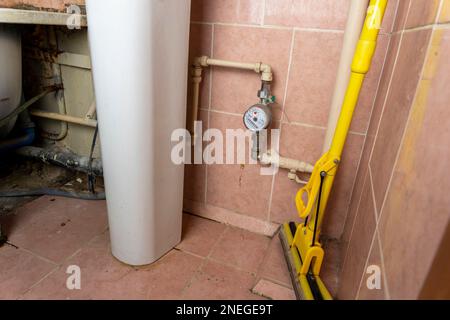 vecchi tubi dell'acqua con un contatore dell'acqua di servizio. un vecchio bagno sporco Foto Stock