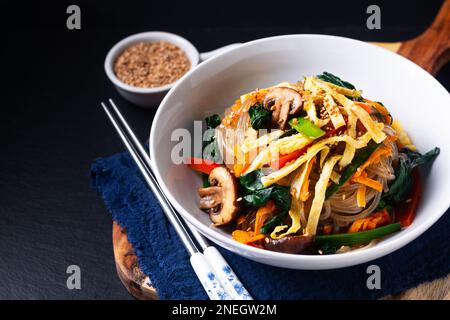 Concetto alimentare Japchae fatto in casa noodle di patate coreane su sfondo nero Foto Stock