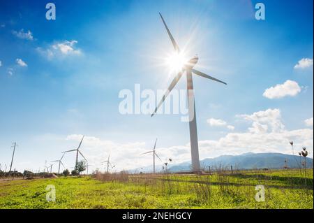 Turbina eolica sull'erba verde sopra il cielo nuvoloso blu. Turbine eoliche Windmill Energy Farm. Foto Stock